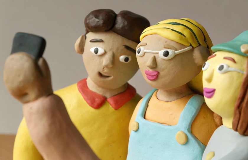 KI-Bild mit Knetfiguren: Zwei Mädchen und ein Junge machen ein Selfie von sich.