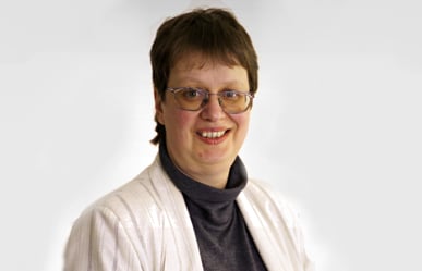 Portrait von Joan Kristin Bleicher, Frau mit Kurzhaarschnitt und Brille lächelt vor weißem Hintergrund.