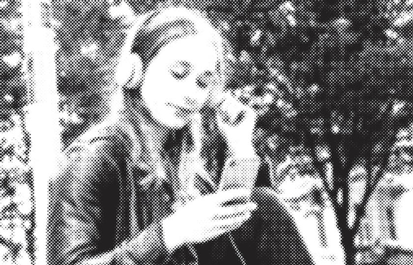 Junge Frau mit Kopfhörern schaut ins Smartphone.