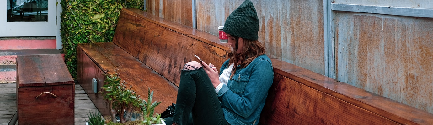 young girl with smartphone sitting on a bench