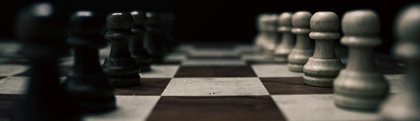White and black pieces face each other on a black-and-white chessboard.