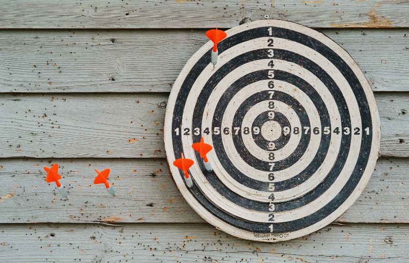 Dartscheibe mit roten Pfeilen an einer Wand.