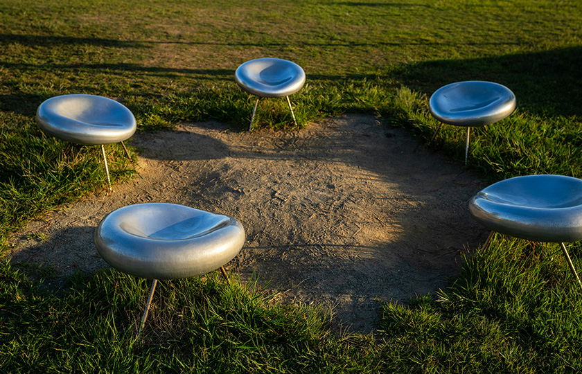 Einige futuristische Stühle stehen im Kreis auf einer grünen Wiese