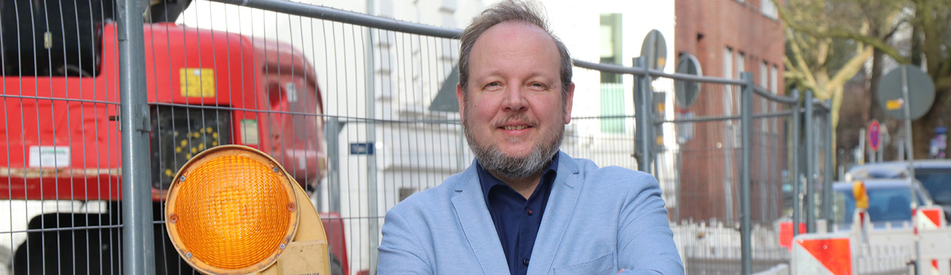 Portrait of Stephan Dreyer in front of a construction fence