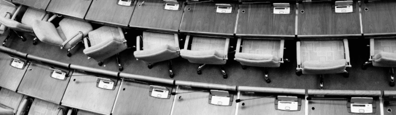 Empty rows of swivel chairs in a meeting hall or parliament chamber.