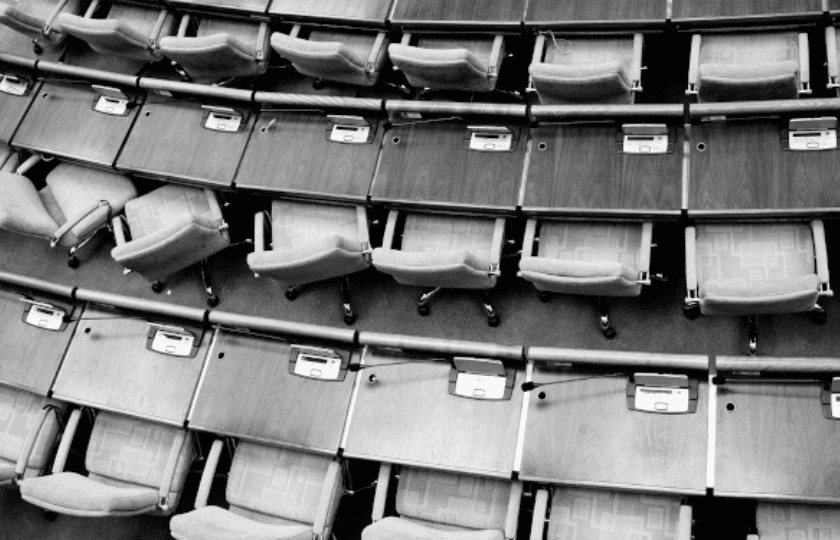 Empty rows of swivel chairs in a meeting hall or parliament chamber.