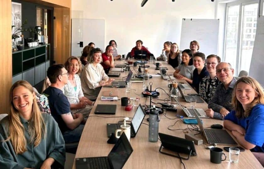 Situation im Workshop: an einem langen Konferenztisch arbeitet eine Gruppe Forschender konzentriert an ihren Laptops